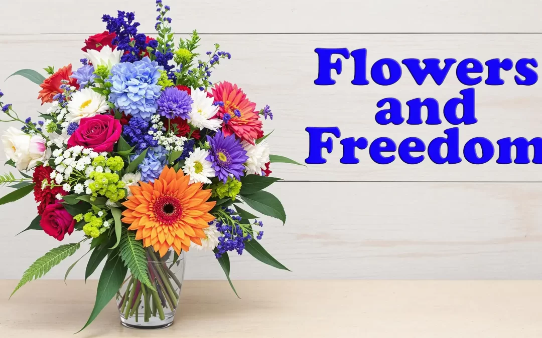Patriotic flower arrangement featuring red roses, white lilies, and blue delphinium in a rustic wooden box with a small American flag, set against a backdrop of a waving U.S. flag and soft natural lighting, symbolizing 4th of July celebration and the theme of Flowers and Freedom.